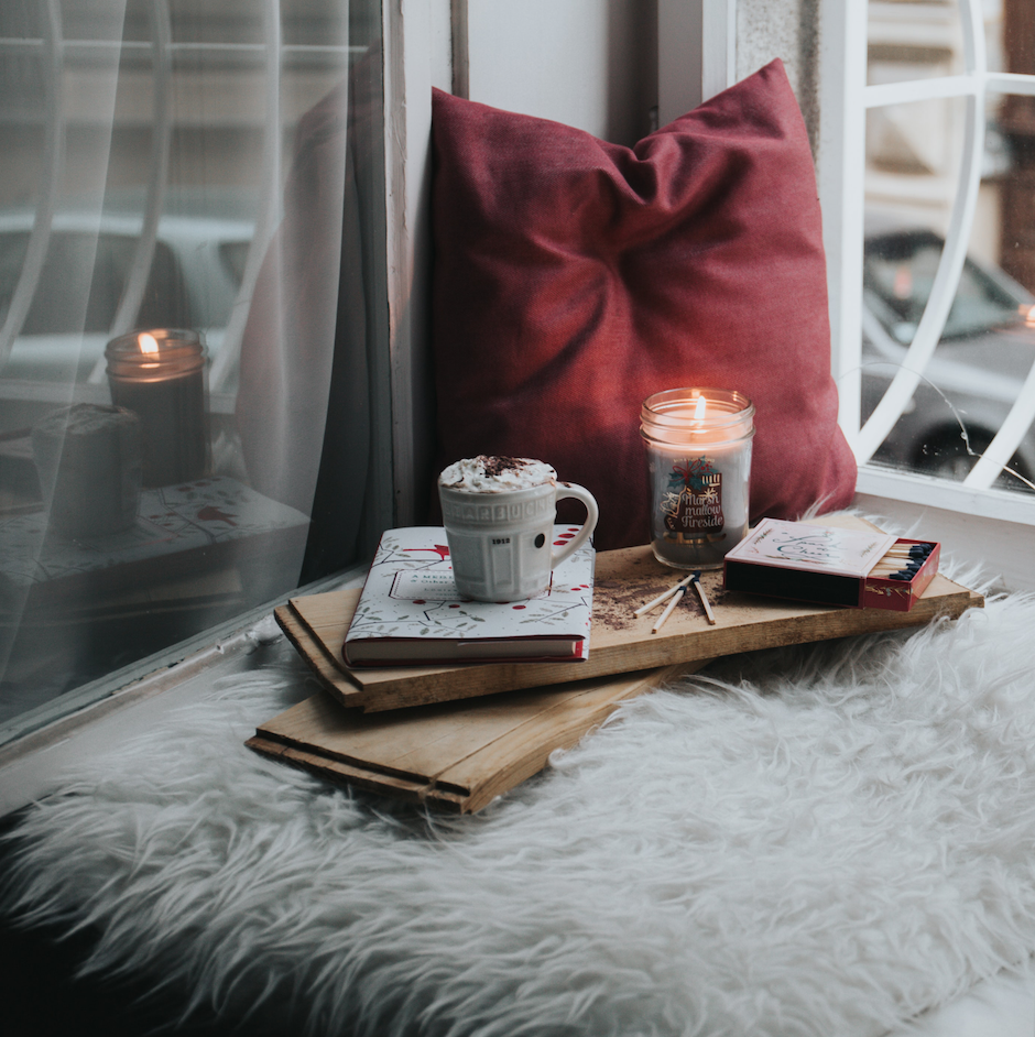 Photo of a cozy winter window nook with pillow and candles
