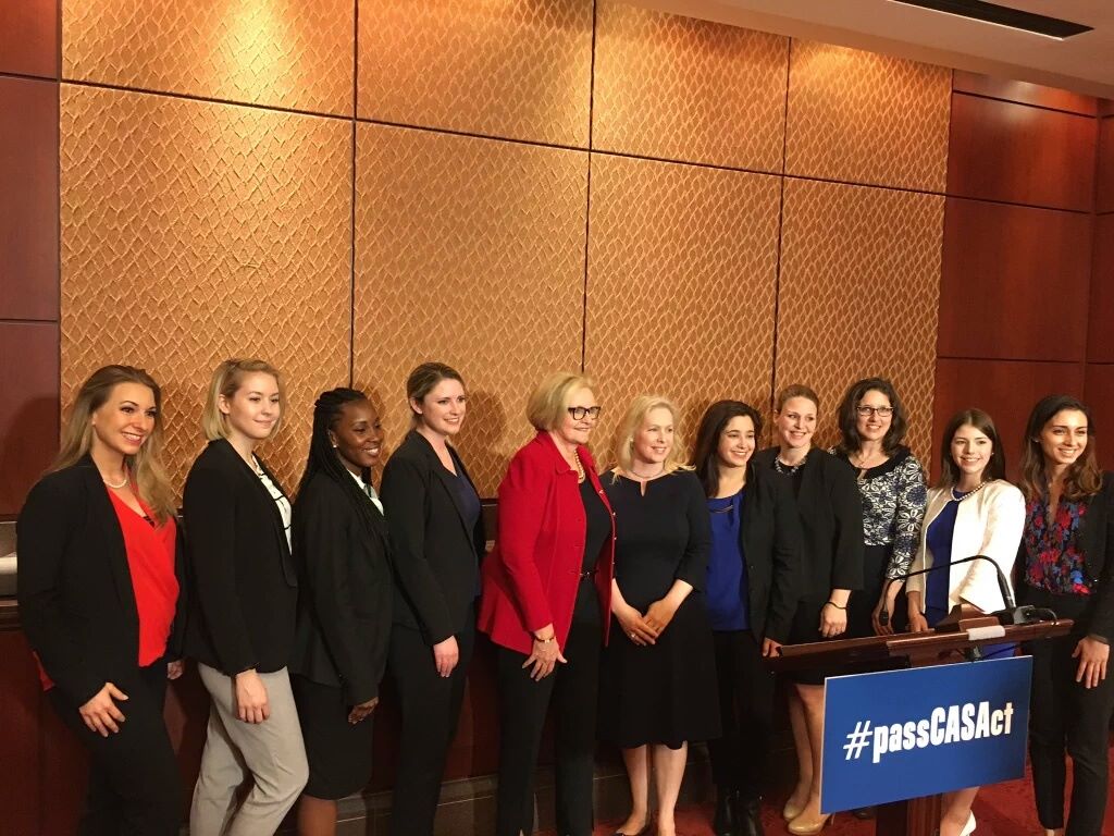 Members of congress, RAINN staff, and other anti-sexual assault advocates pose behind a podium. The podium holds a sign reading "Pass CASA act."